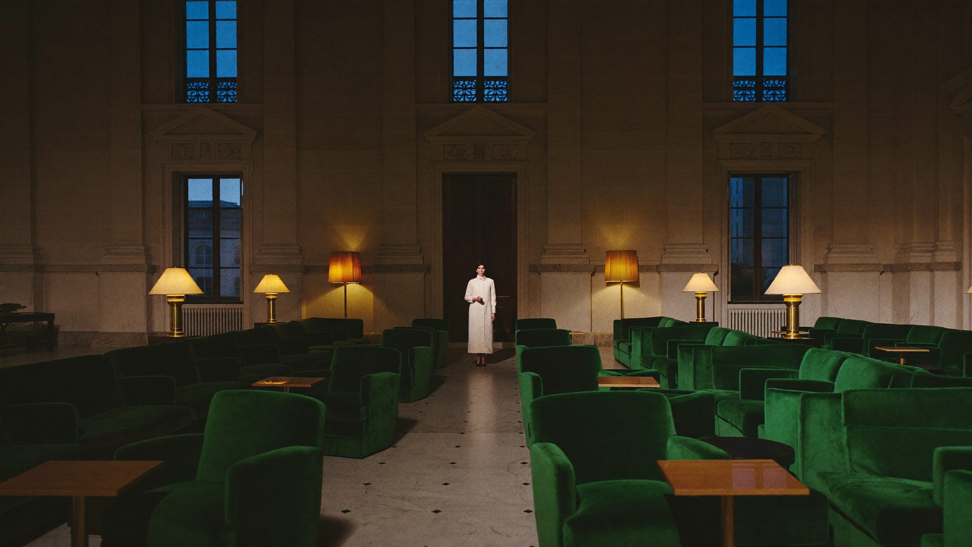 Figure in a cream coat in a grand marble hotel lobby